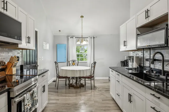 a kitchen with stainless steel appliances a table chairs sink and stove top oven