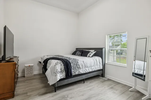 a bed sitting in a bedroom next to a window with wooden floor