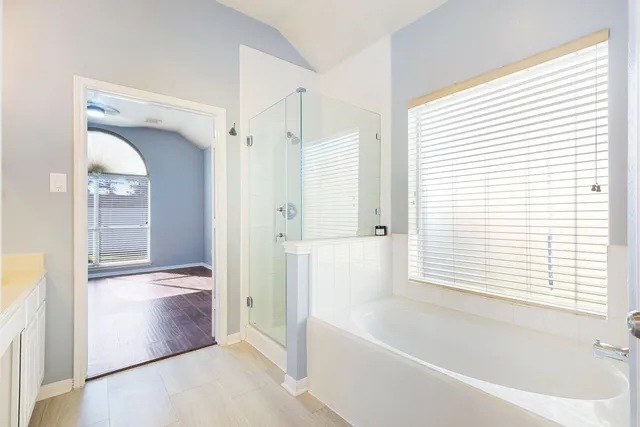 a spacious bathroom with a tub sink and mirror