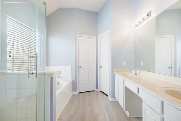 a spacious bathroom with a tub sink and mirror