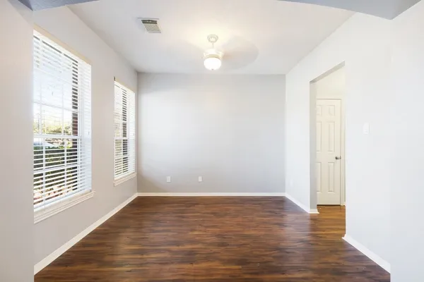 a view of an empty room with wooden floor and a window