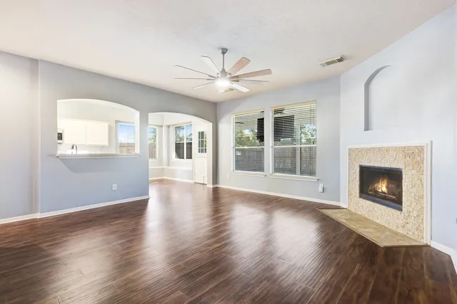a view of an empty room with wooden floor and a fireplace