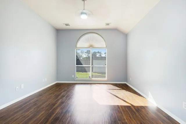 an empty room with wooden floor and windows