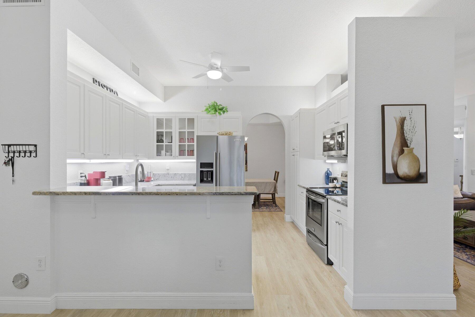 7961 Exeter Boulevard East, Unit 102 Tamarac, FL 33321 - Photo 14 of 46 a kitchen with stainless steel appliances a microwave a sink a stove and cabinets