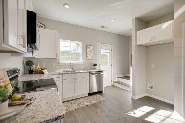 a kitchen with stainless steel appliances granite countertop a stove top oven a sink dishwasher a dining table and chairs with wooden floor