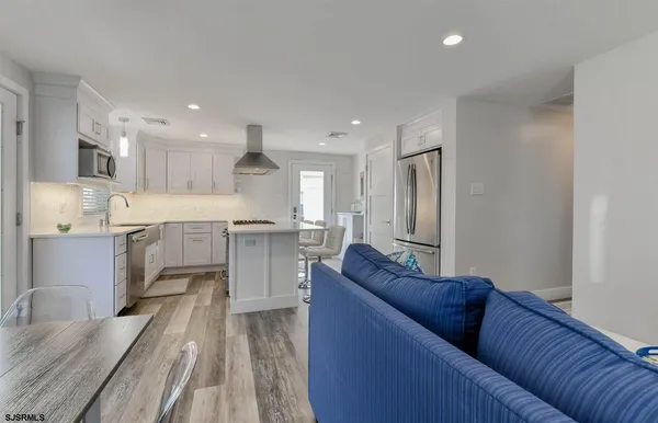 a living room with stainless steel appliances kitchen island granite countertop furniture and a wooden floor