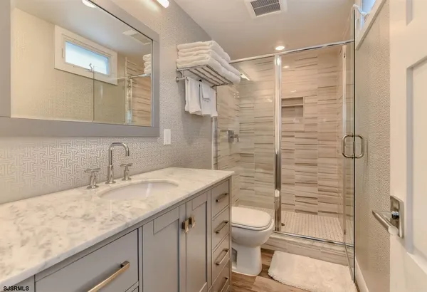 a bathroom with a granite countertop sink toilet and shower