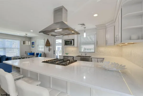 a kitchen with a stove a sink a refrigerator and white cabinets with wooden floor