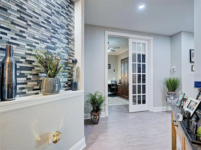 a view of a hallway and a livingroom with wooden floor and a potted plant