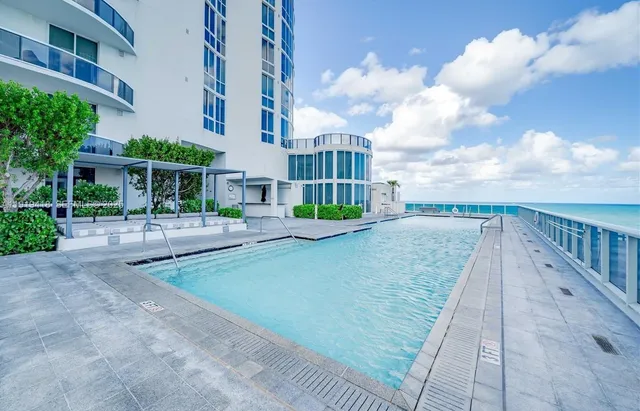 a front view of a residential apartment building with a yard and seating space