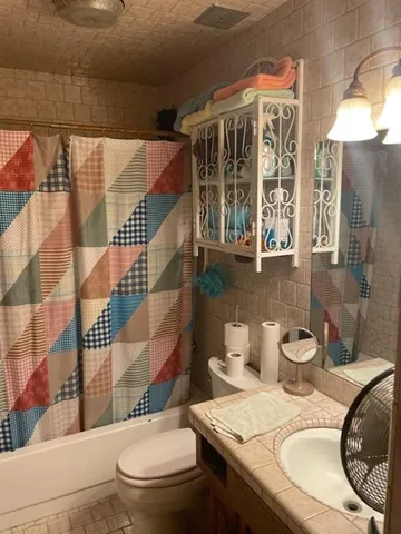a bathroom with a granite countertop toilet sink and mirror
