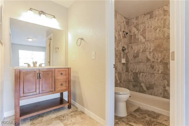 a bathroom with a granite countertop sink a toilet and shower