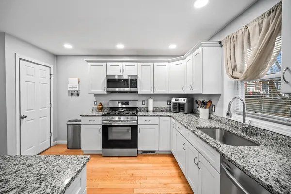 a large kitchen with stainless steel appliances granite countertop a sink stove and refrigerator
