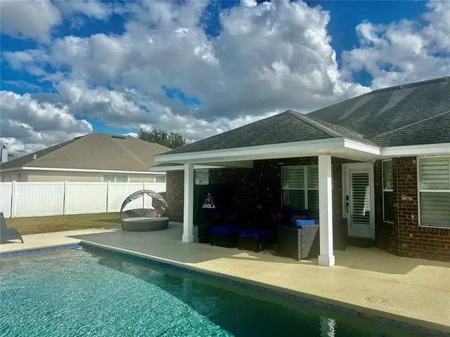 a backyard of a house with table and chairs under an umbrella