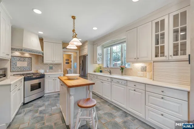 a kitchen with granite countertop kitchen island white cabinets and stainless steel appliances