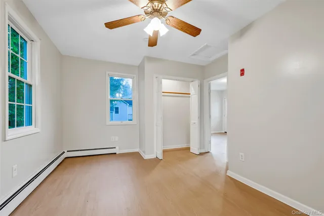 a view of an empty room with window and chandelier fan