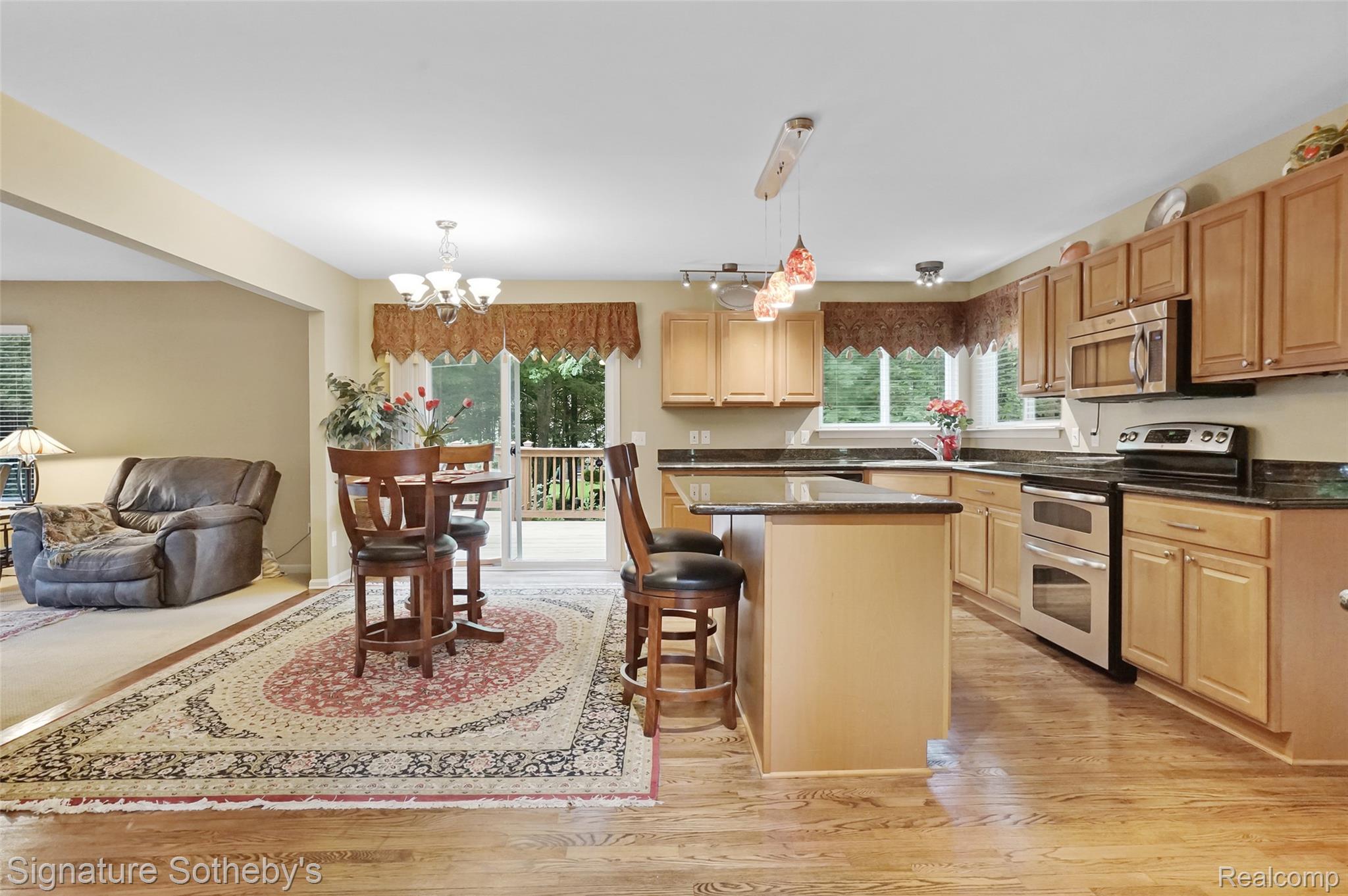 170 Fairhill Way Howell, MI 48843 - Photo 5 of 60 Kitchen featuring wood flooring, maple cabinetry, granite countertops, a kitchen island with snack bar seating, and stainless-steel appliances