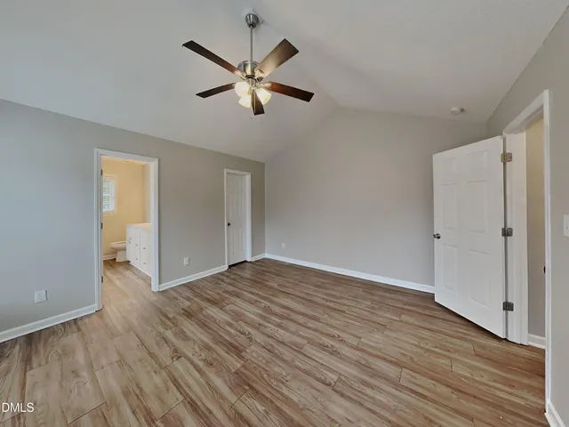 an empty room with wooden floor and ceiling fan