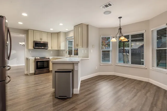 a kitchen with stainless steel appliances granite countertop a refrigerator a stove top oven a sink dishwasher and wooden floor