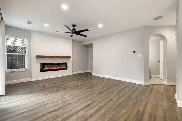 a view of an empty room with wooden floor fireplace and a window