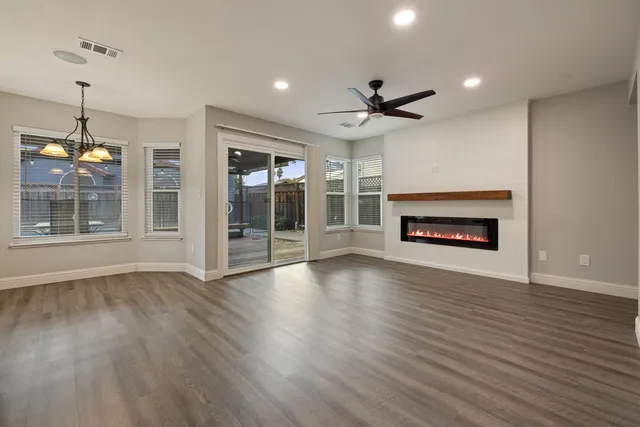 an empty room with wooden floor fireplace and windows