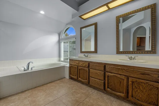 a spacious bathroom with a granite countertop sink mirror and bathtub