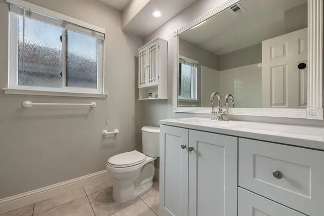 a bathroom with a toilet a sink a mirror and vanity