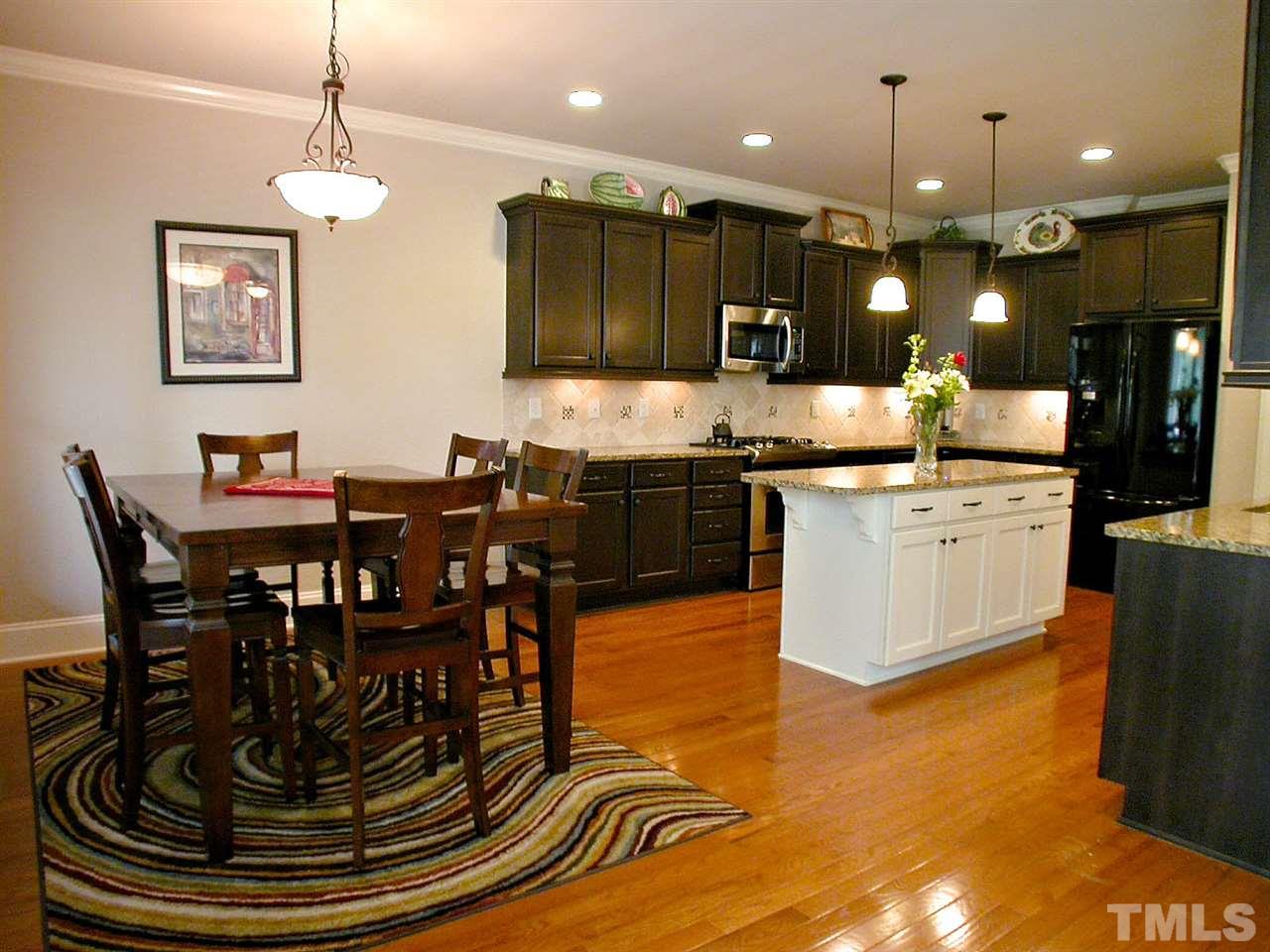 12349 Beestone Lane Raleigh, NC 27614 - Photo 8 of 25 a kitchen with kitchen island granite countertop a stove a sink a dining table and chairs
