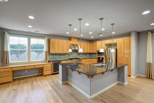 a large kitchen with stainless steel appliances granite countertop a large window and a counter space