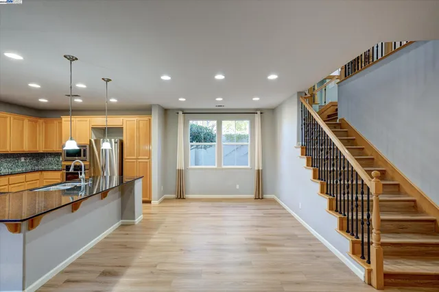 a view of a kitchen with kitchen island granite countertop wooden floor stainless steel appliances and a sink