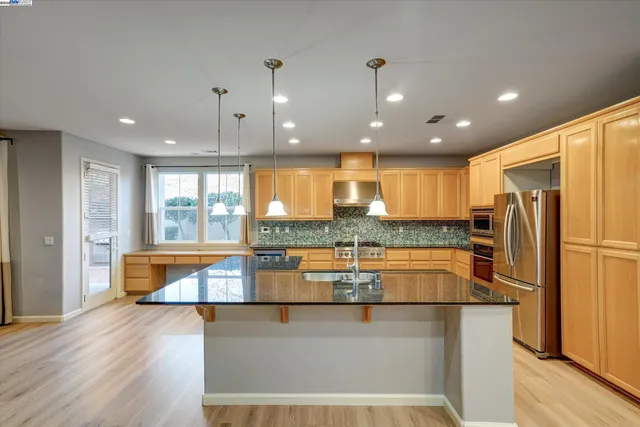 a kitchen with stainless steel appliances granite countertop a refrigerator and a stove