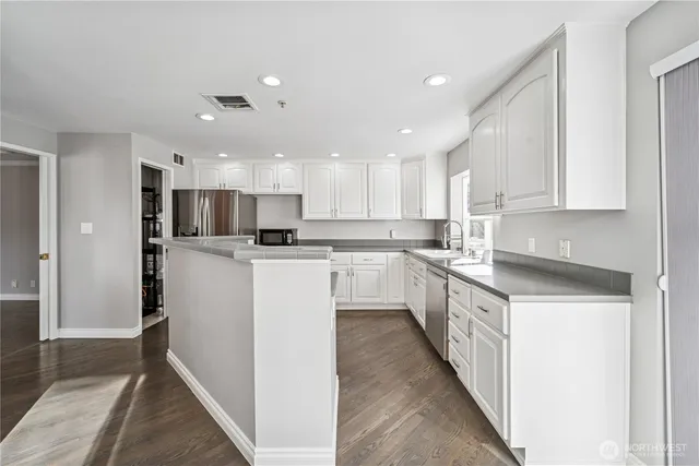 a kitchen with kitchen island a sink stainless steel appliances and cabinets