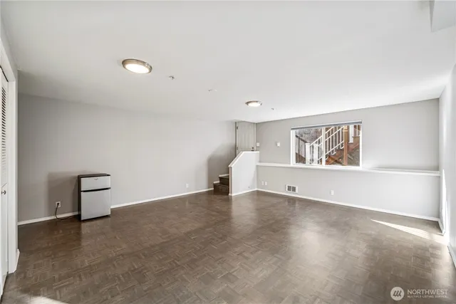 a view of an empty room with window and wooden floor
