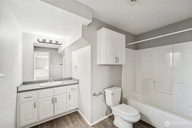 a spacious bathroom with a granite countertop sink toilet a mirror and shower