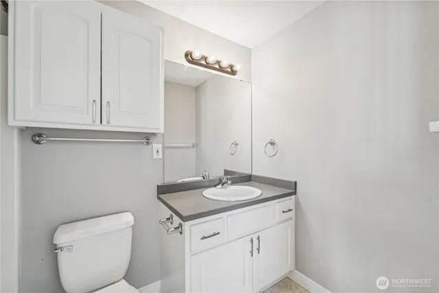 a bathroom with a granite countertop toilet and a sink