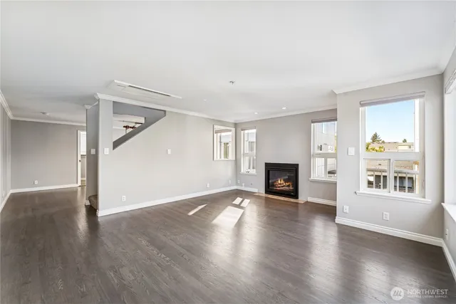 an empty room with wooden floor fireplace and windows
