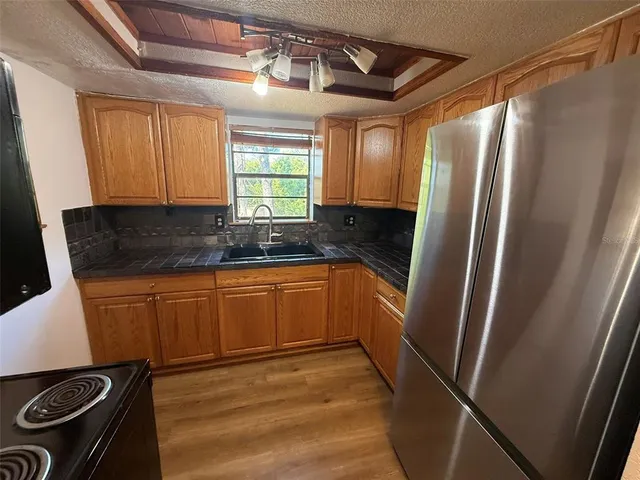 a kitchen with refrigerator a stove a sink and dishwasher with wooden floor