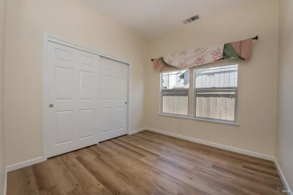 an empty room with wooden floor cabinet and windows