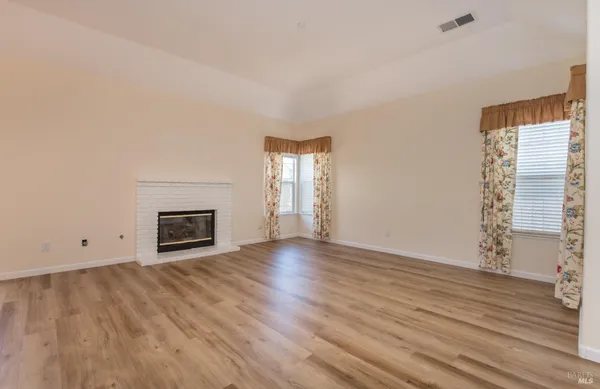 a view of empty room with wooden floor and fireplace