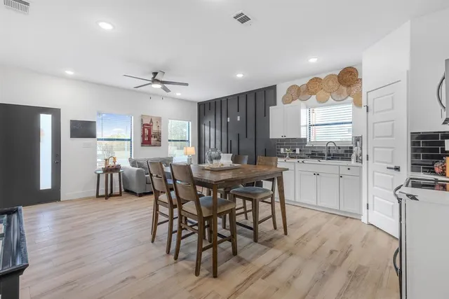 a kitchen with stainless steel appliances a dining table chairs refrigerator sink and cabinets