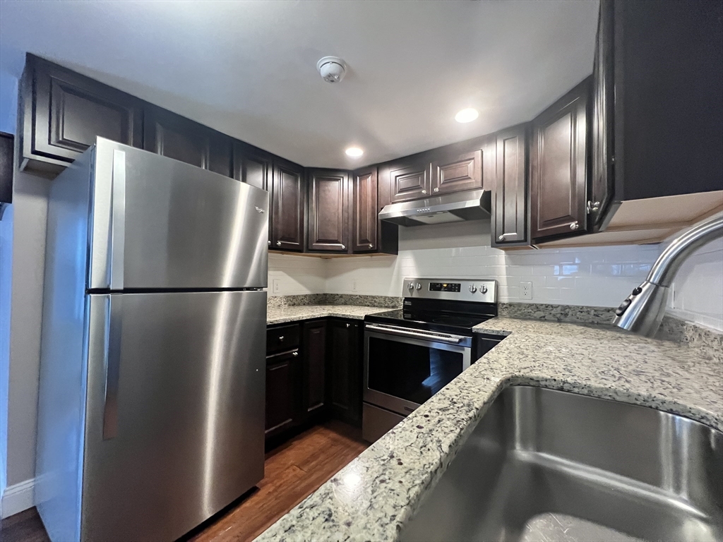 166 Pleasant Street, Unit 1 Marblehead, MA 01945 - Photo 4 of 10 a kitchen with a refrigerator sink and wooden cabinets
