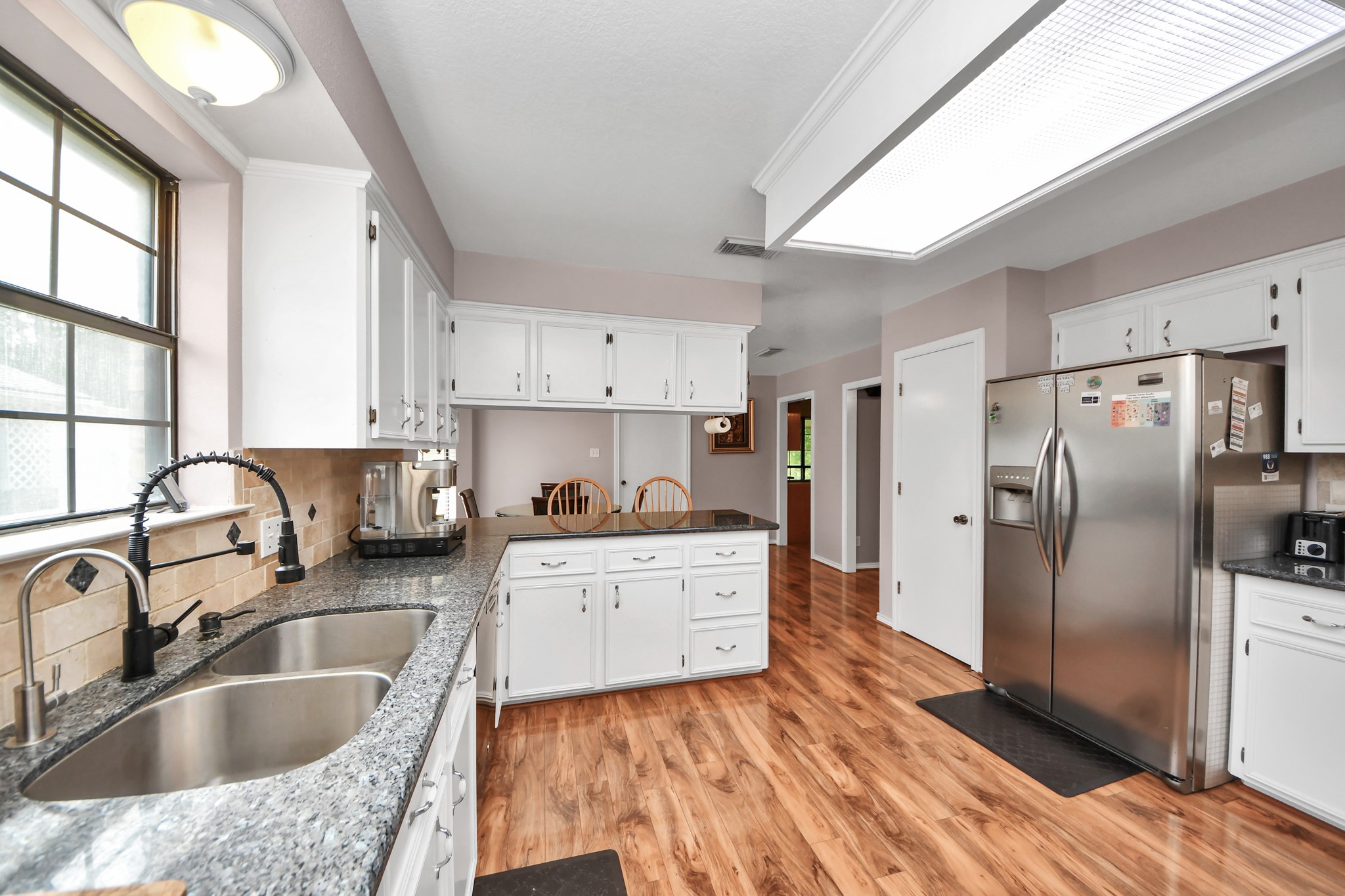 12746 Roy Road Pearland, TX 77581 - Photo 13 of 47 Bright and spacious kitchen featuring granite countertops, stainless steel appliances, and ample white cabinetry. The room is accented with wood flooring and a large window for natural light.