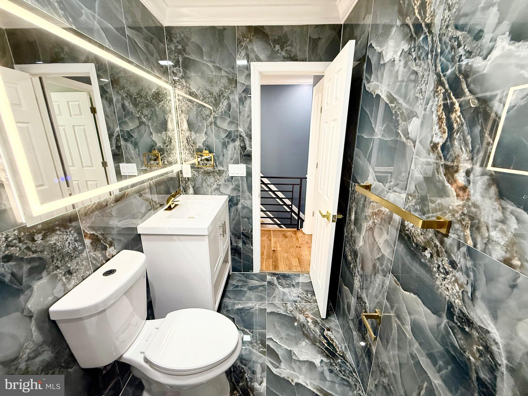 1942 South 56th Street Philadelphia, PA 19143 - Photo 28 of 36 a white toilet sitting next to a bathroom sink and a mirror