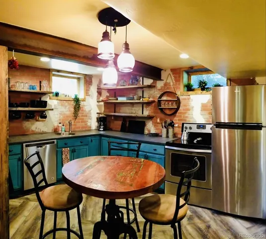a kitchen with stainless steel appliances granite countertop a table chairs and a refrigerator