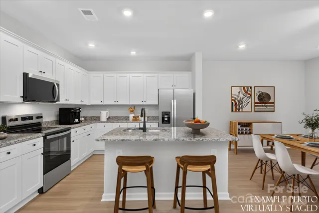 a kitchen with stainless steel appliances granite countertop a stove a sink a dining table and chairs