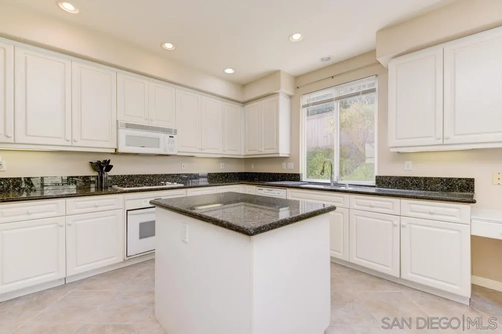 3224 Rancho Arroba Carlsbad, CA 92009 - Photo 16 of 35 a kitchen with granite countertop white cabinets and white appliances