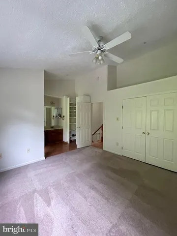an empty room with closet and a ceiling fan
