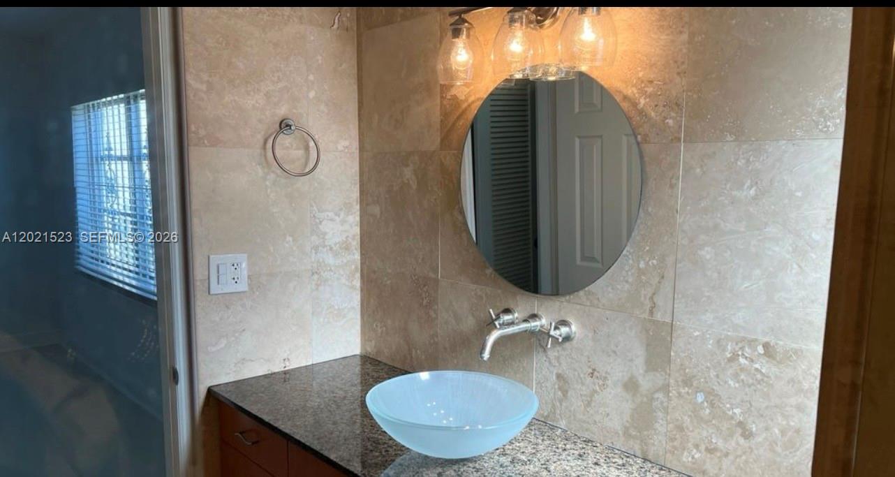 9159 Southwest 77th Avenue, Unit 101 Miami, FL 33156 - Photo 5 of 12 a bathroom with a sink and mirror