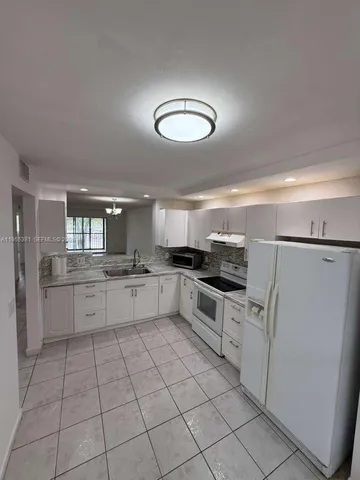 a kitchen with white cabinets a sink and white appliances