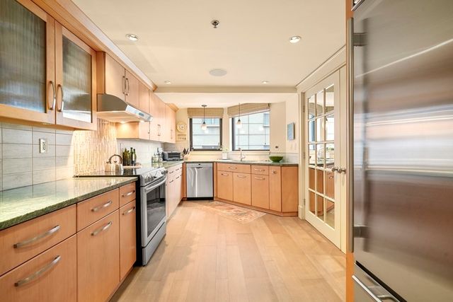 a large kitchen with a sink stainless steel appliances and cabinets